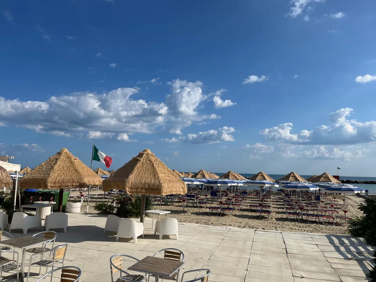 Terrazza bar con vista sulla spiaggia e ombrelloni in paglia
